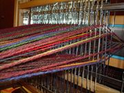 The yarn passes through the heddles in each shaft of this four-shaft table loom. This is a view from the rear of the loom.