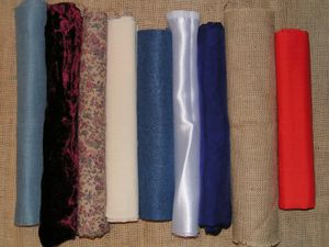 A variety of fabric.  From the left: evenweave cotton, velvet, printed cotton, calico, felt, satin, silk, hessian, polycotton.
